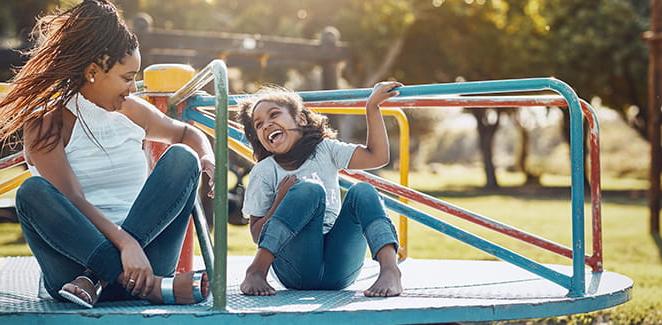 Mother and daughter enjoying a park merry go round